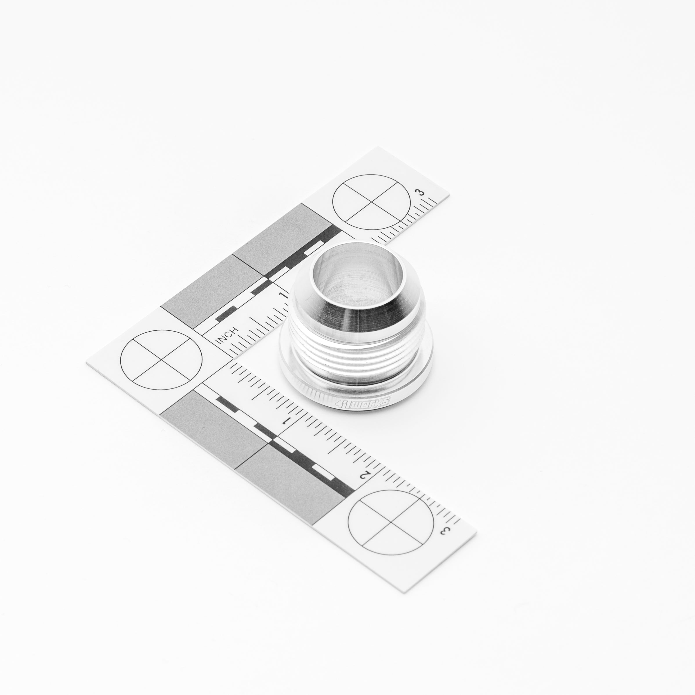 Metal AN fitting on a white background with measurement scale