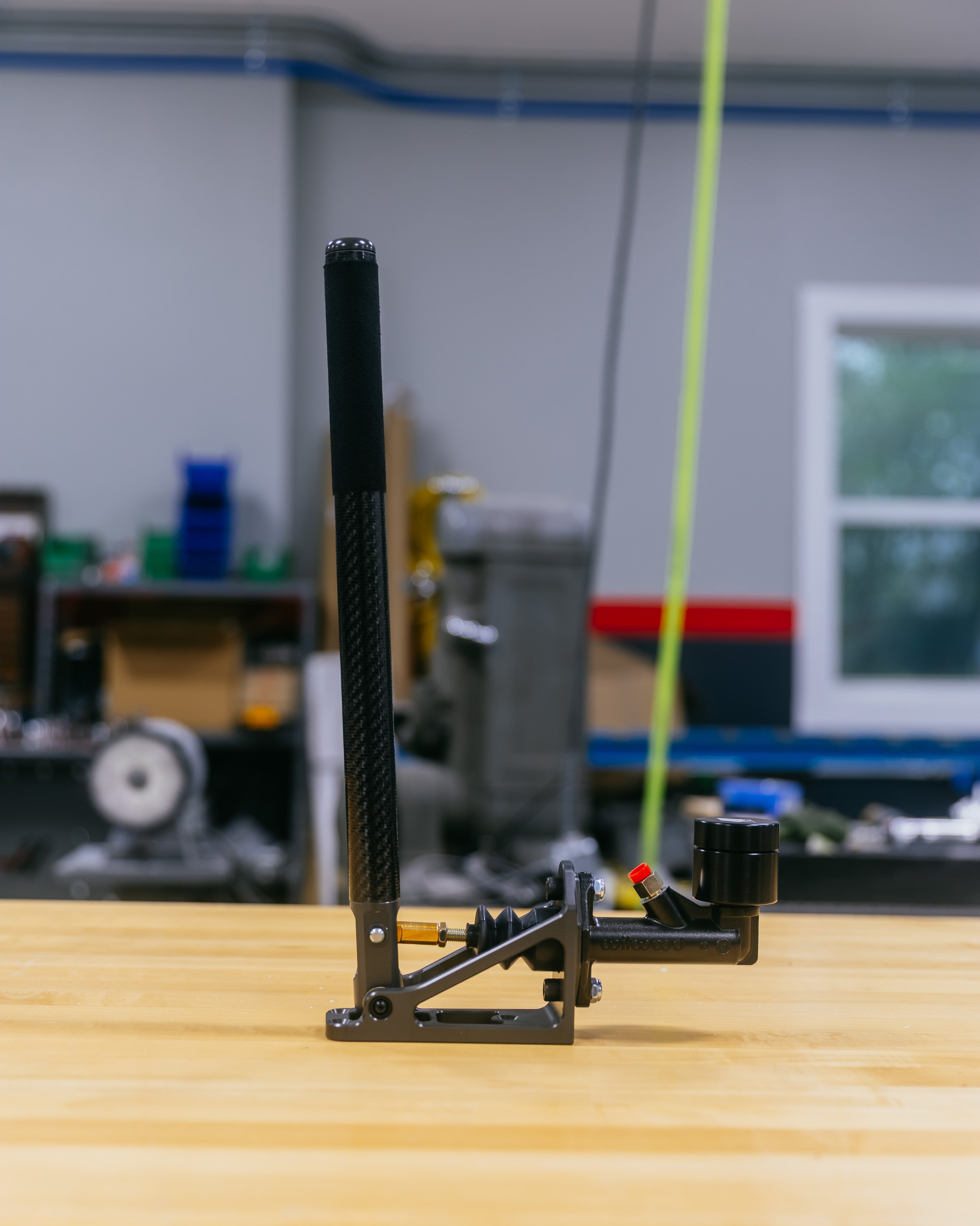 Black mechanical handbrake on a wooden surface with a blurred workshop background