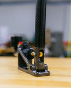 Close-up of a carbon fiber handbrake with a black base on a wooden surface.