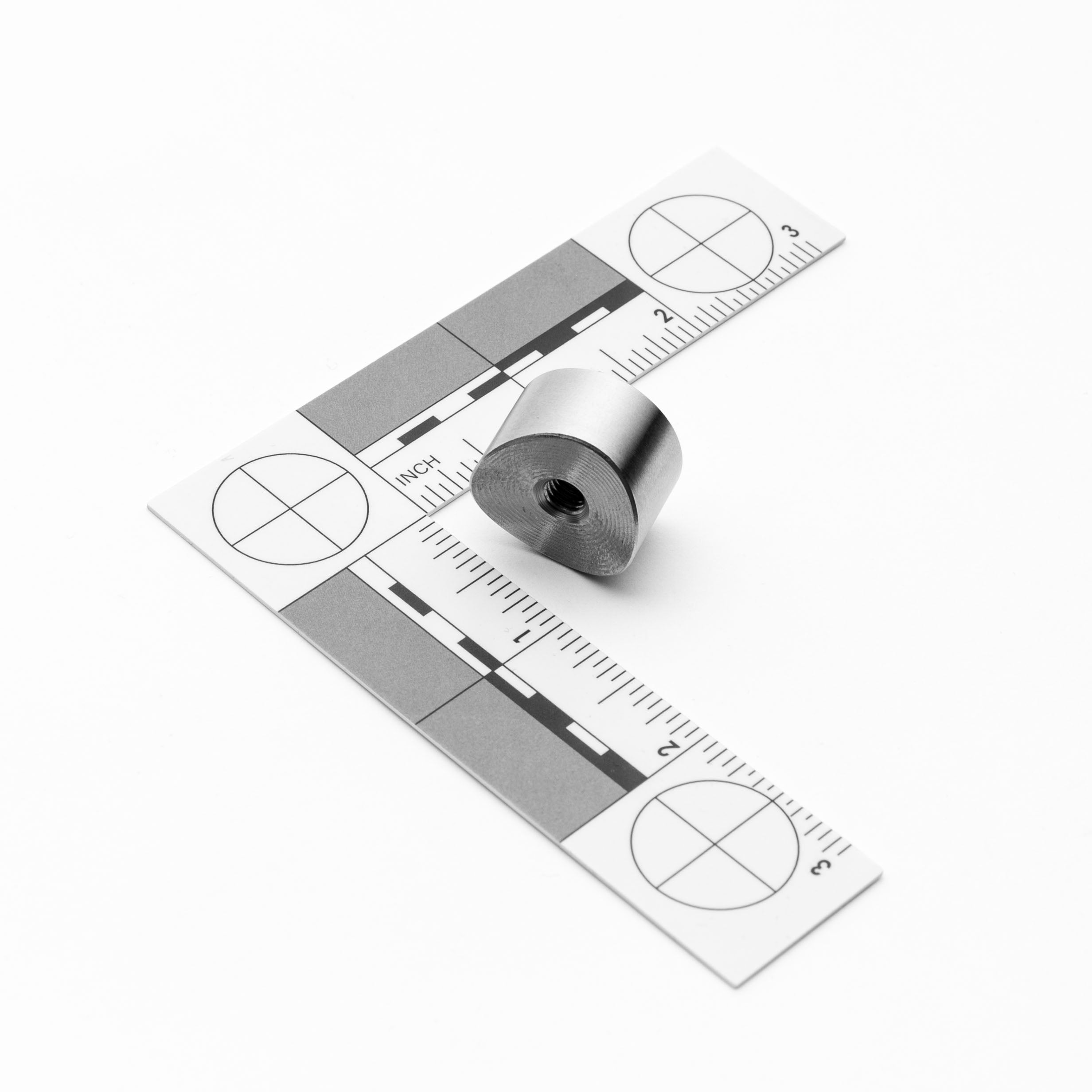 Metallic weld bungs on a ruler with measurement markings