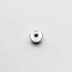 Metallic button with 'M-6' marking on a light gray background