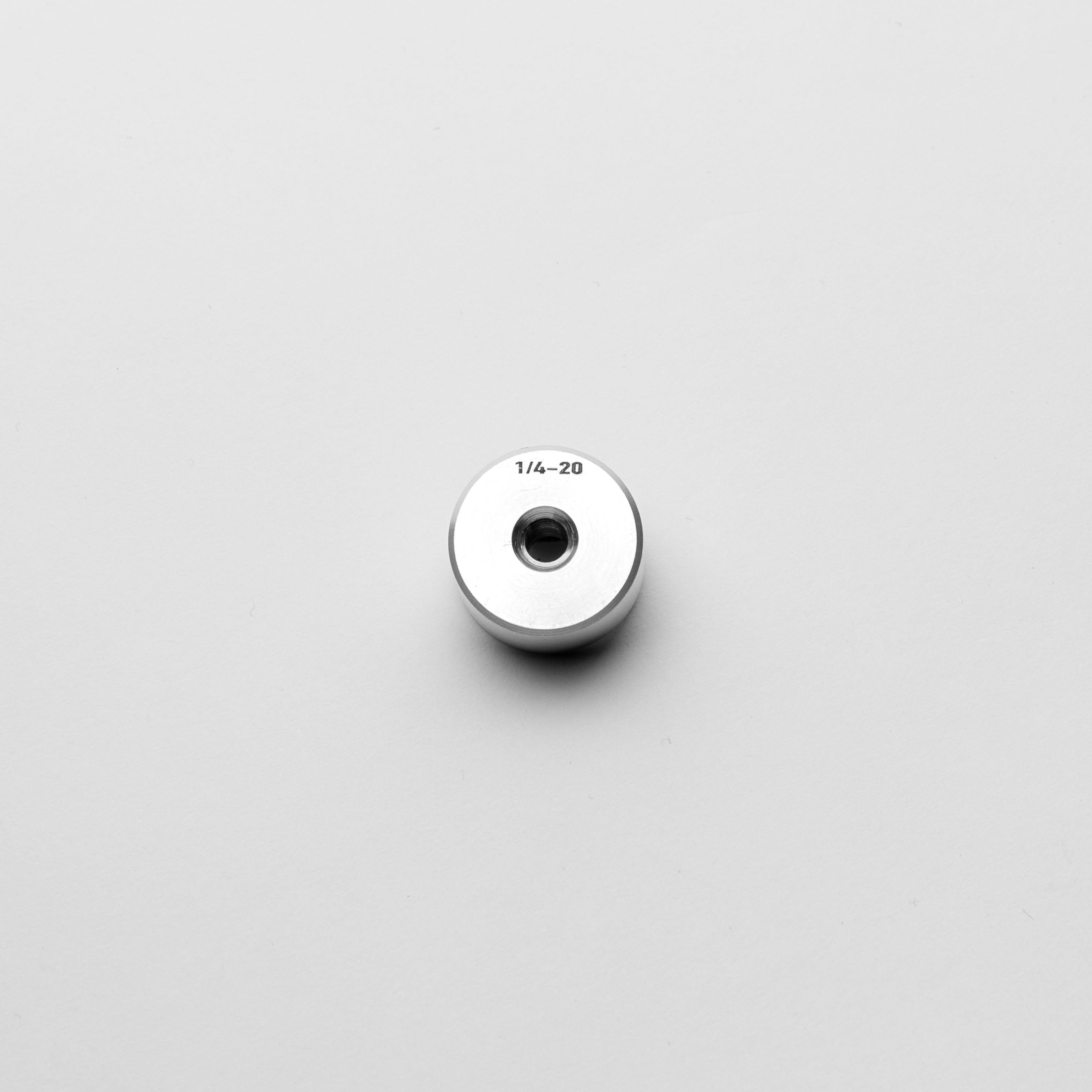 Metallic cylindrical object with threading on a light gray background