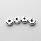 Four metal washers with different thread sizes on a light gray background