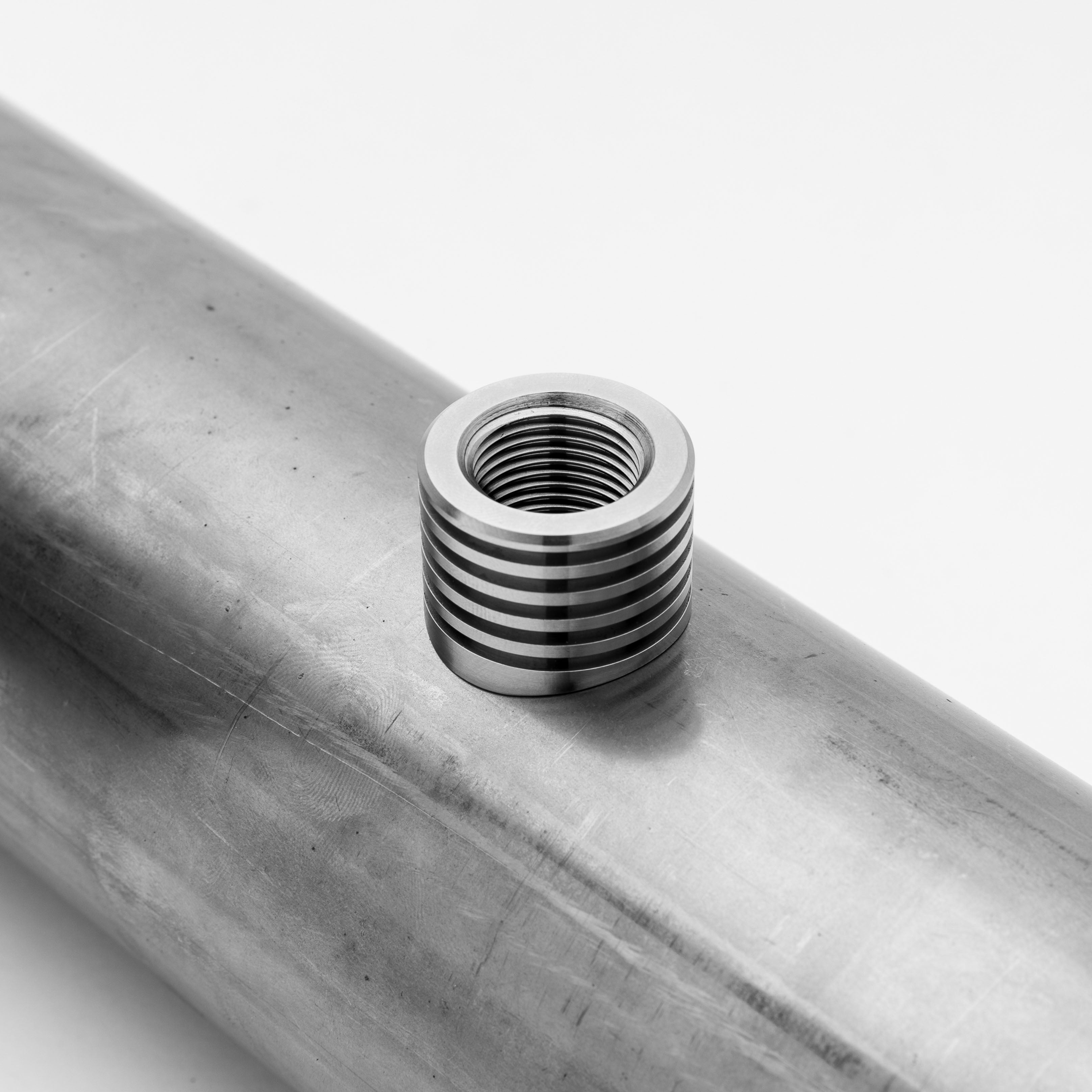 Metallic thread insert on a metal pipe with a white background