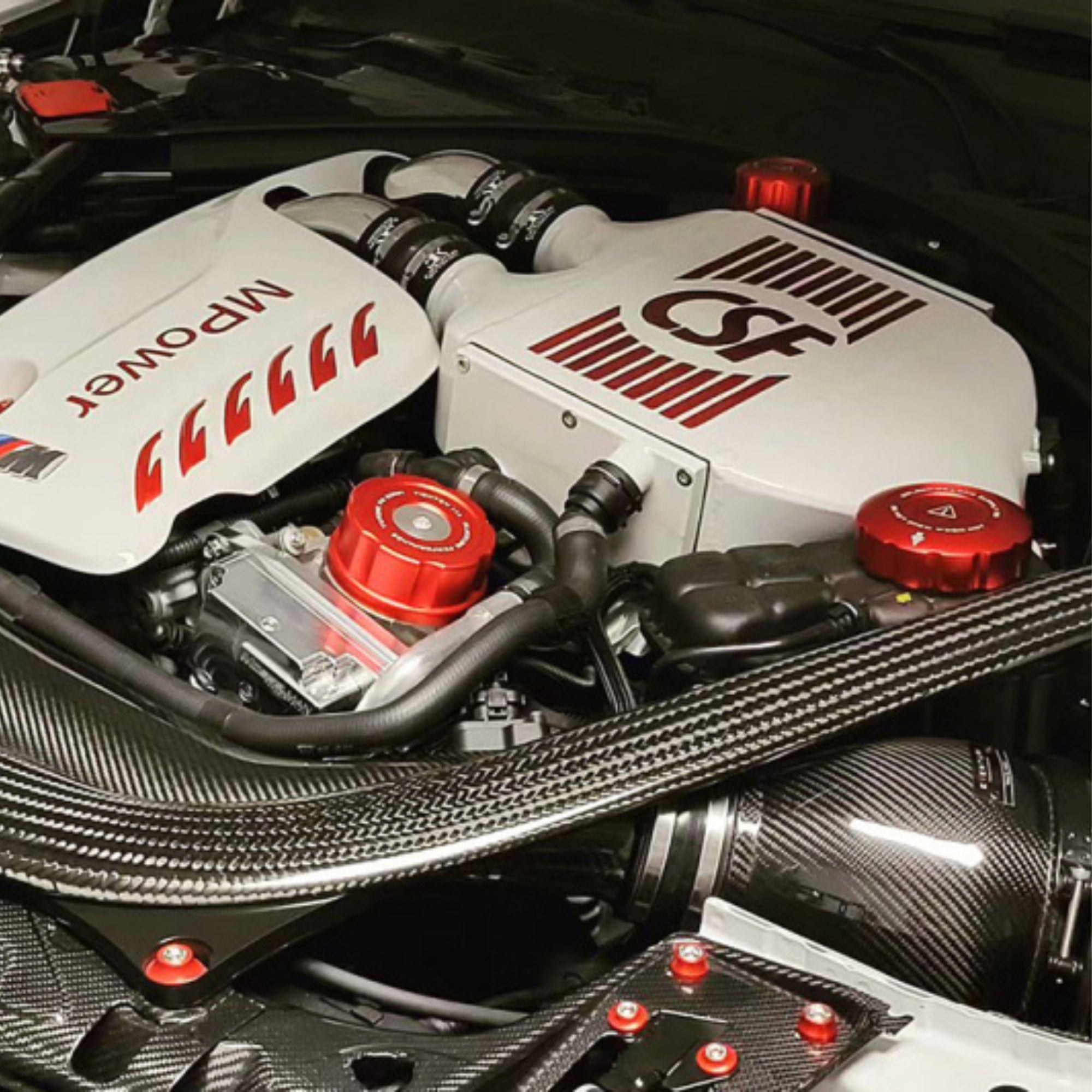 Car engine with 'CSF' and 'M Power' branding on a carbon fiber background