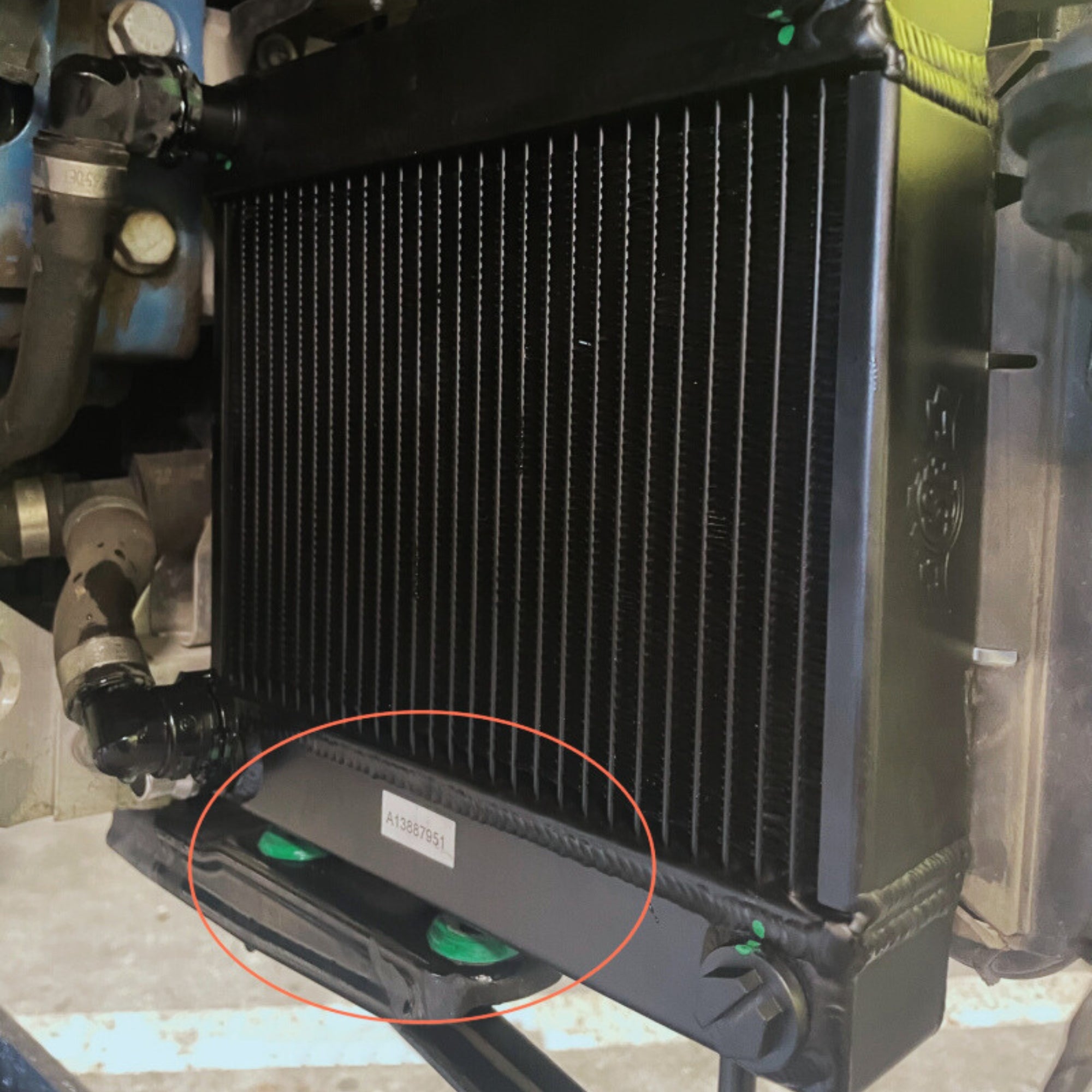 Close-up of a black radiator with a red circle around a part label mounted in car