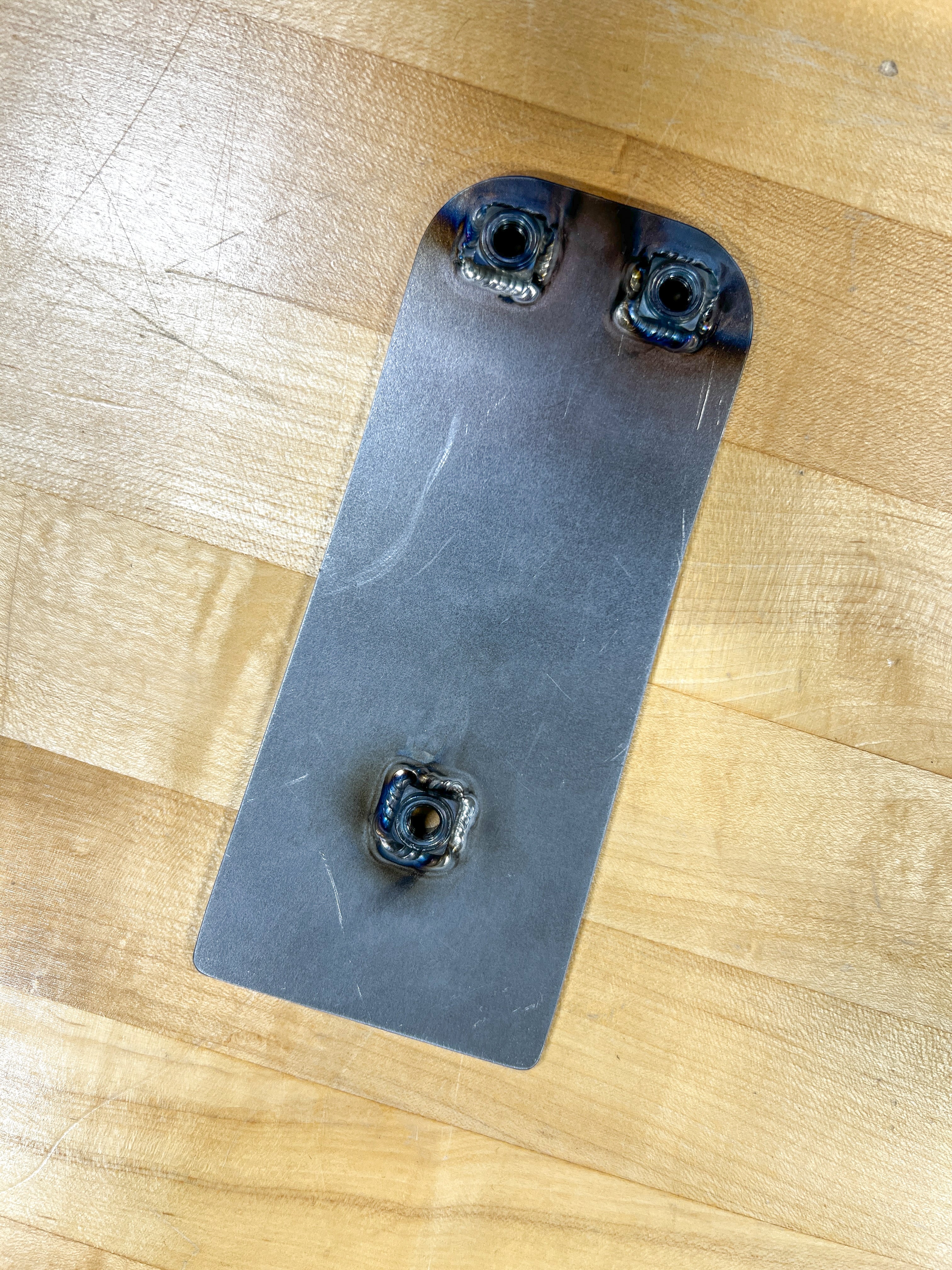 Metal bracket with three screws on a wooden surface