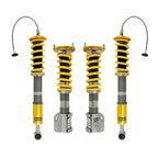 Four Ohlins shock absorber coilovers with yellow springs on a white background