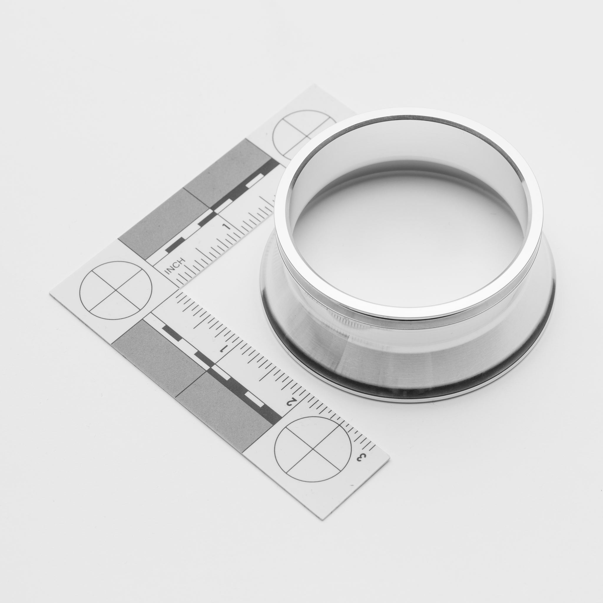 Metallic ring with a ruler for scale on a white background