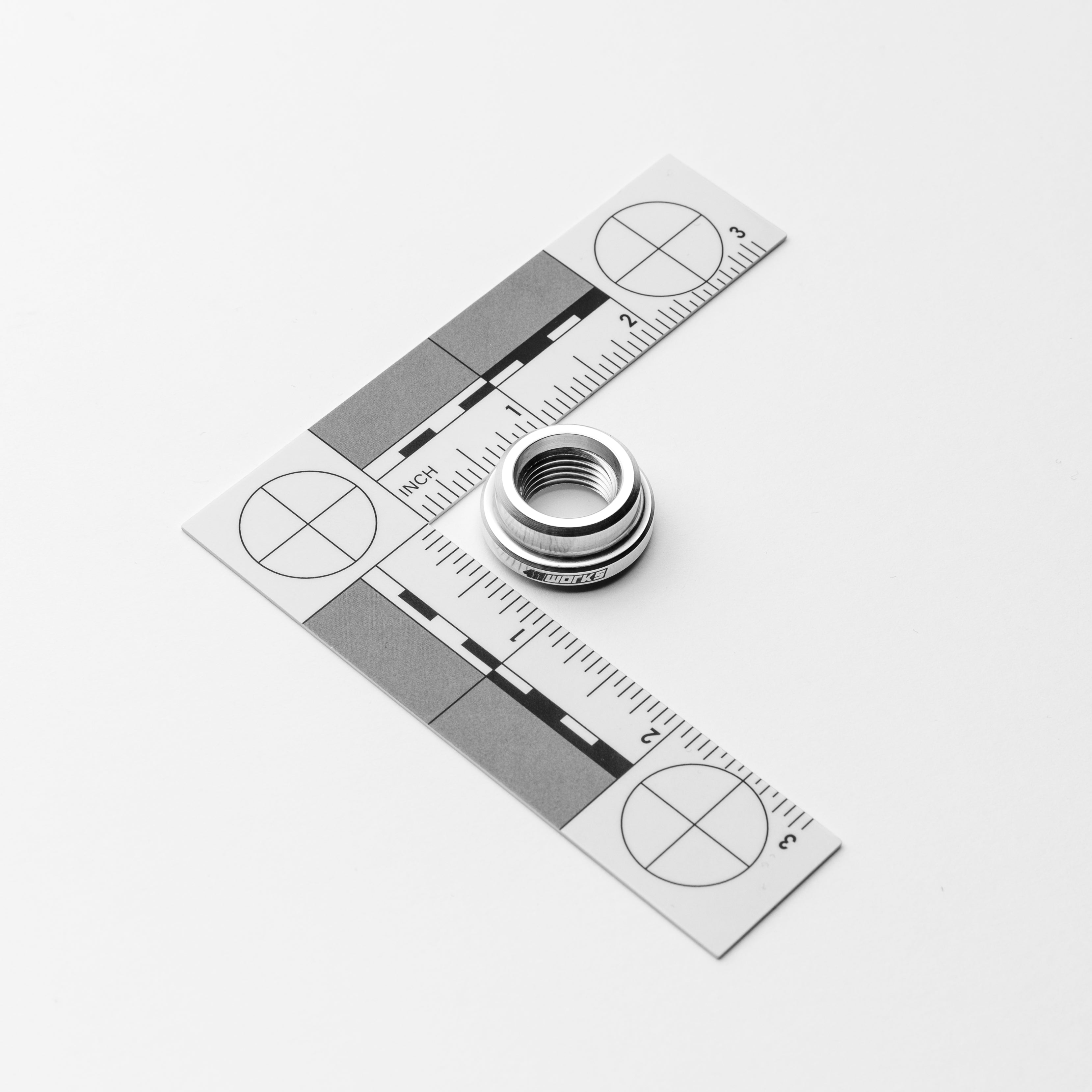 Metal weld bung on a white background with a square ruler