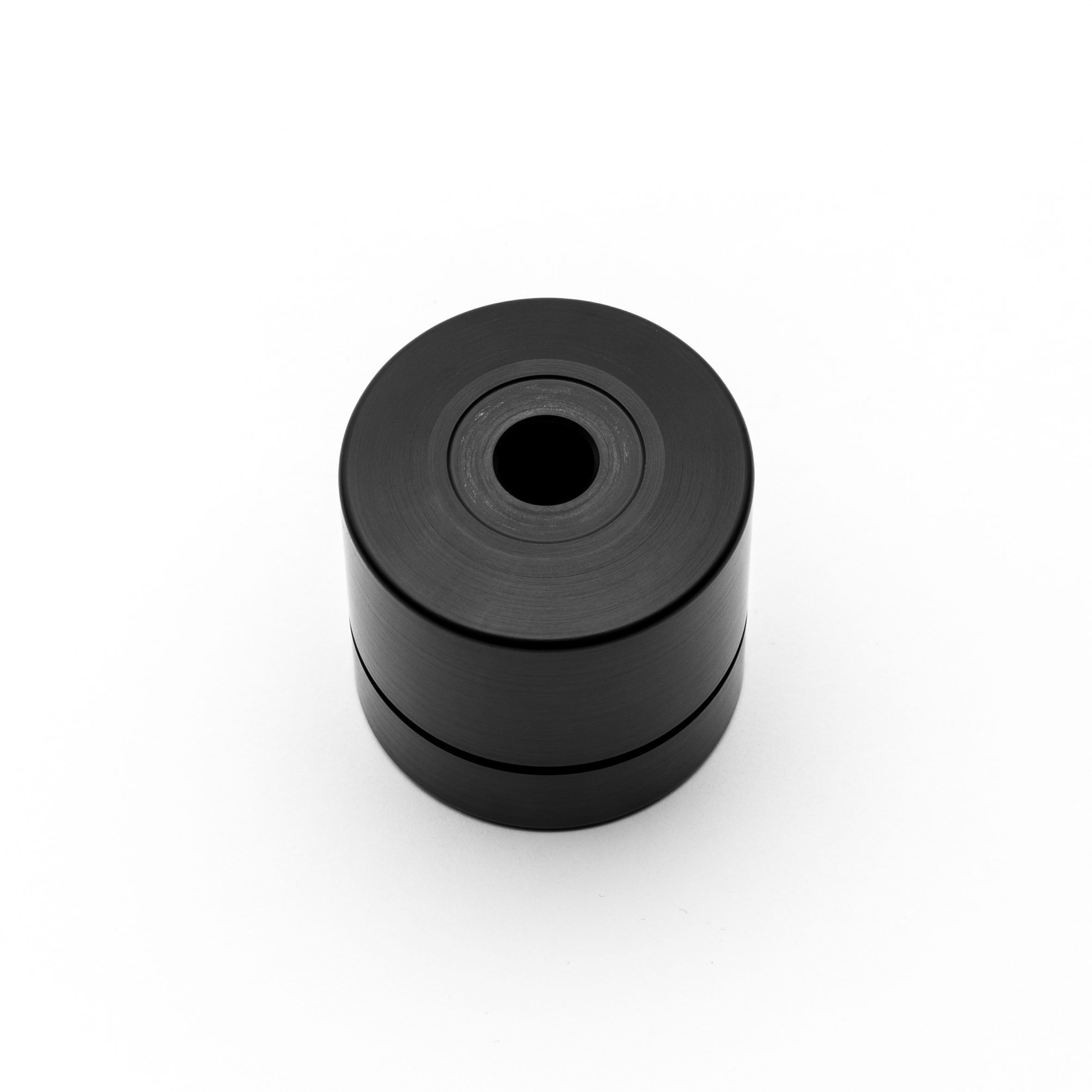 Black cylindrical object with a central hole on a white background