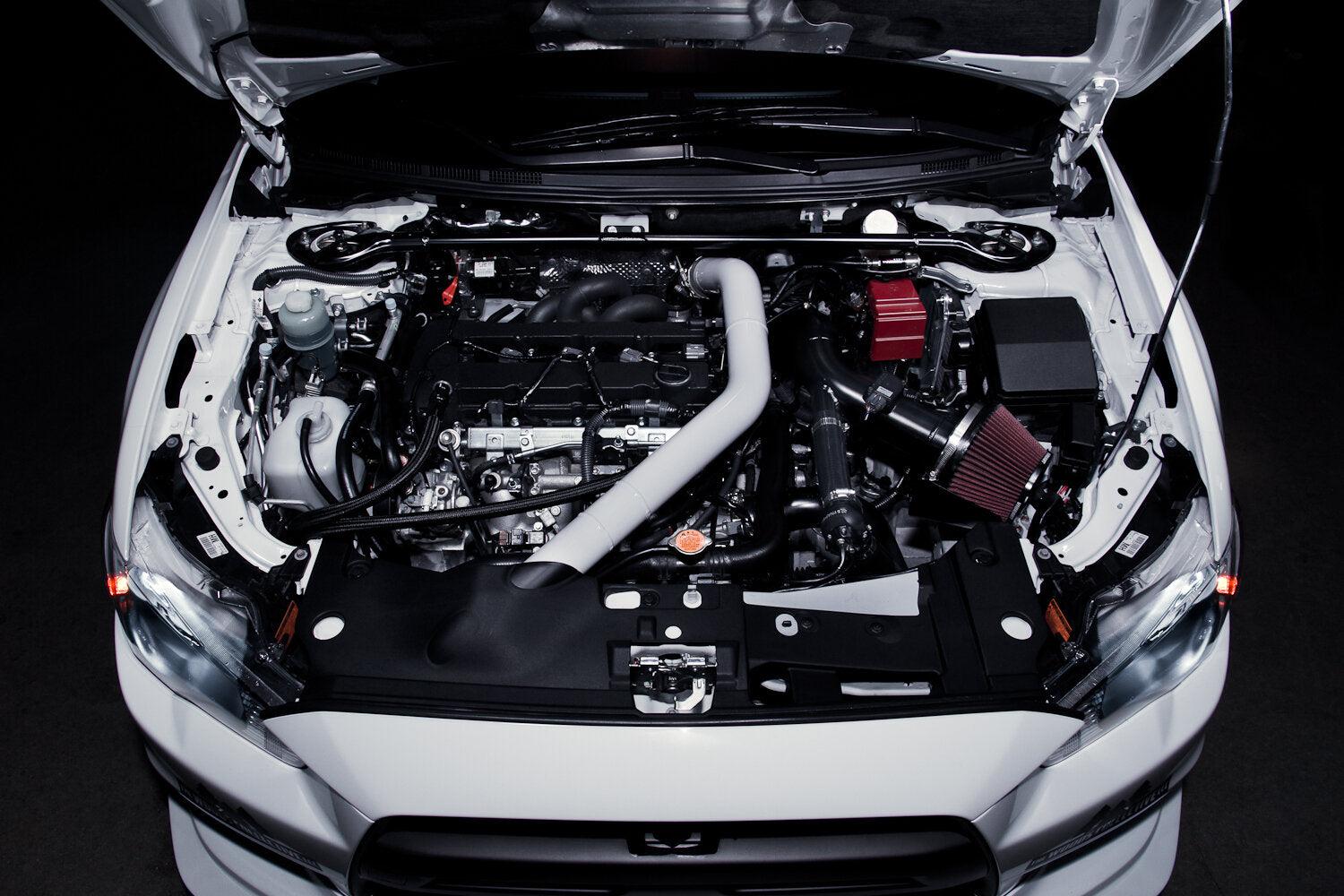 Mitsubishi EVO engine compartment with open hood on a black background